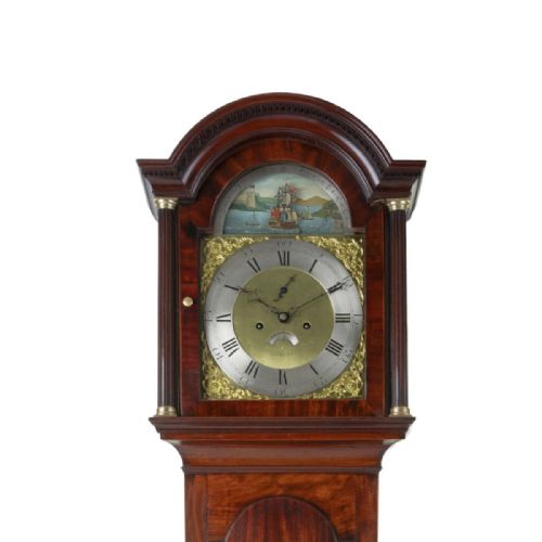 fig 2. An antique Georgian flame mahogany longcase clock featuring an arched hood with brass-capped pillars and a silvered brass dial topped with a painted rocking ship automaton.