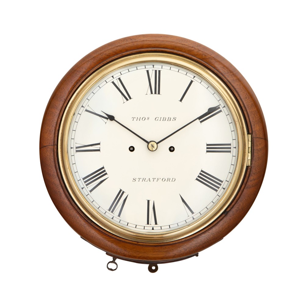 A circular antique mahogany wall clock featuring an off-white dial with black Roman numerals, brass bezel, and signed Thos Gibbs Stratford.
