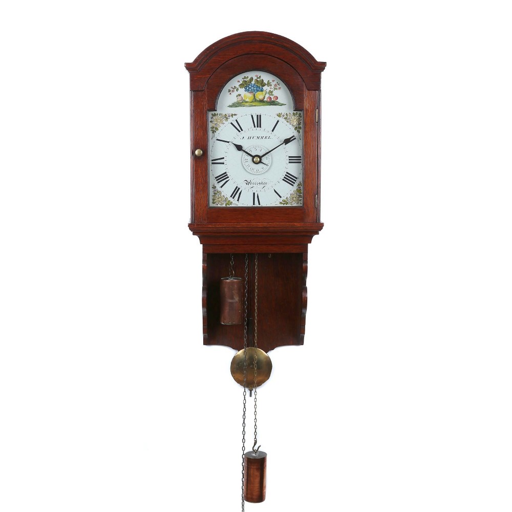 An antique dark wood hooded wall clock with a glazed arch door, painted dial featuring Roman numerals and fruit illustration, with hanging weights and pendulum below.