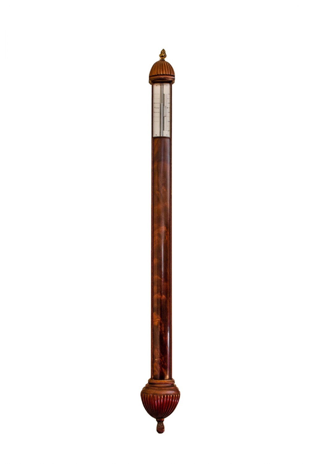 A slender mahogany stick barometer with a brass top finial, framed register plate, and carved fluted cistern cover at the base.