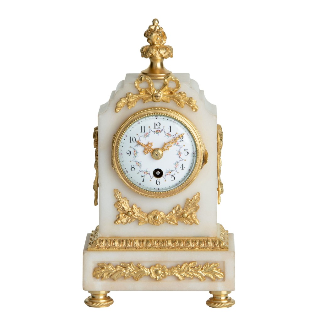 A small white alabaster timepiece clock decorated with gilt-bronze ribbon and foliage mounts and a hand-painted enamel dial.