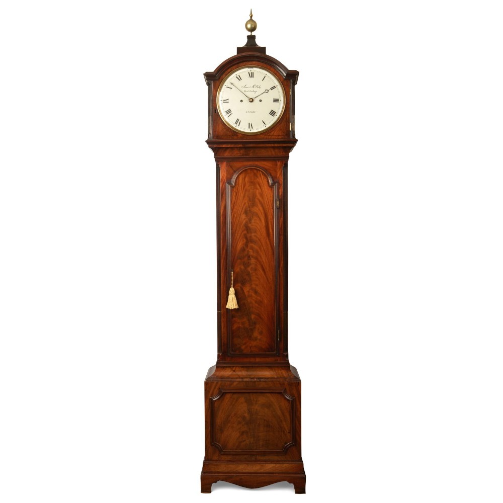 A tall Georgian flame mahogany longcase clock featuring an arched hood with a brass ball finial, a white enamel dial signed James McCabe London, and a moulded trunk door.