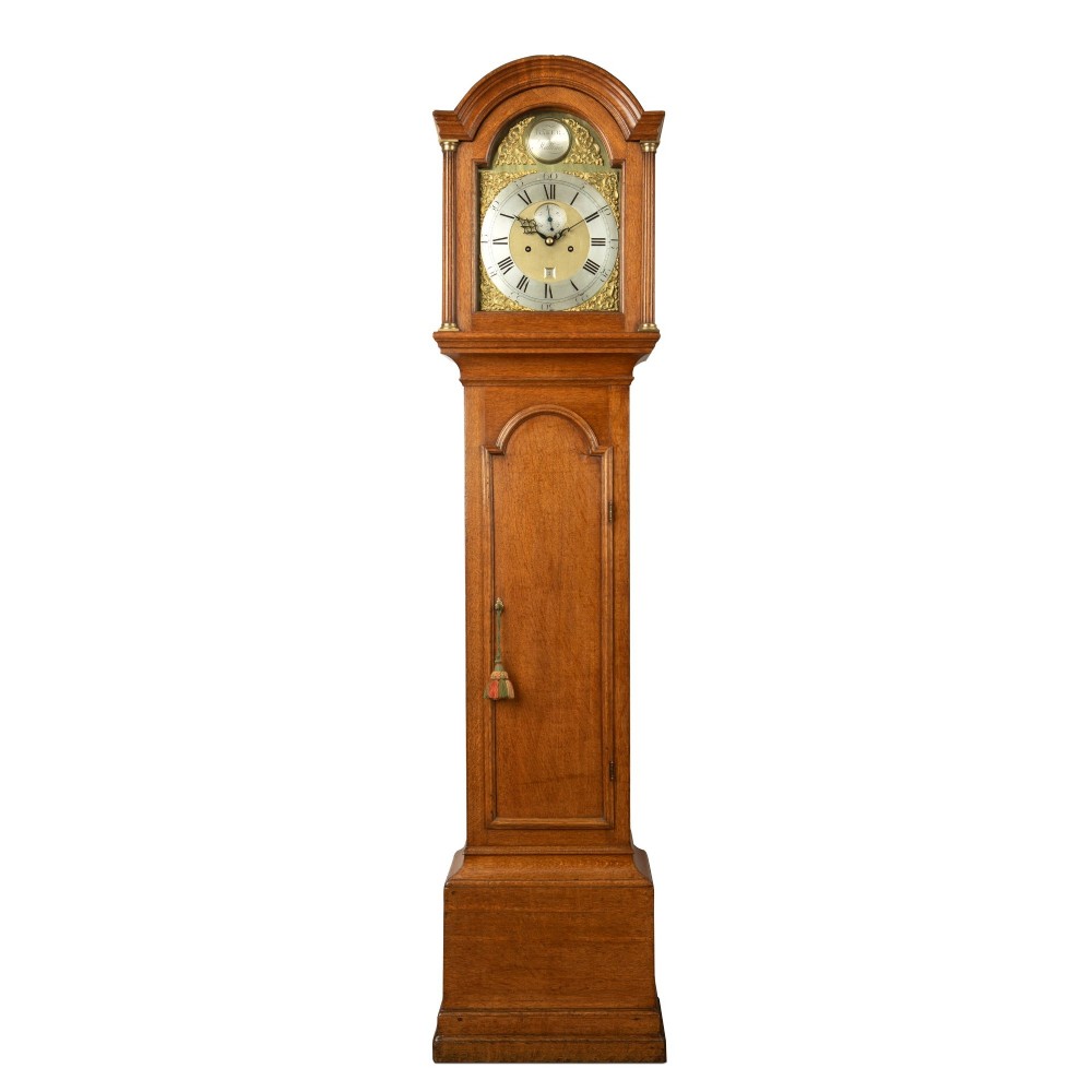An 18th-century Georgian oak longcase clock featuring a brass dial with corner spandrels and an arched hood.