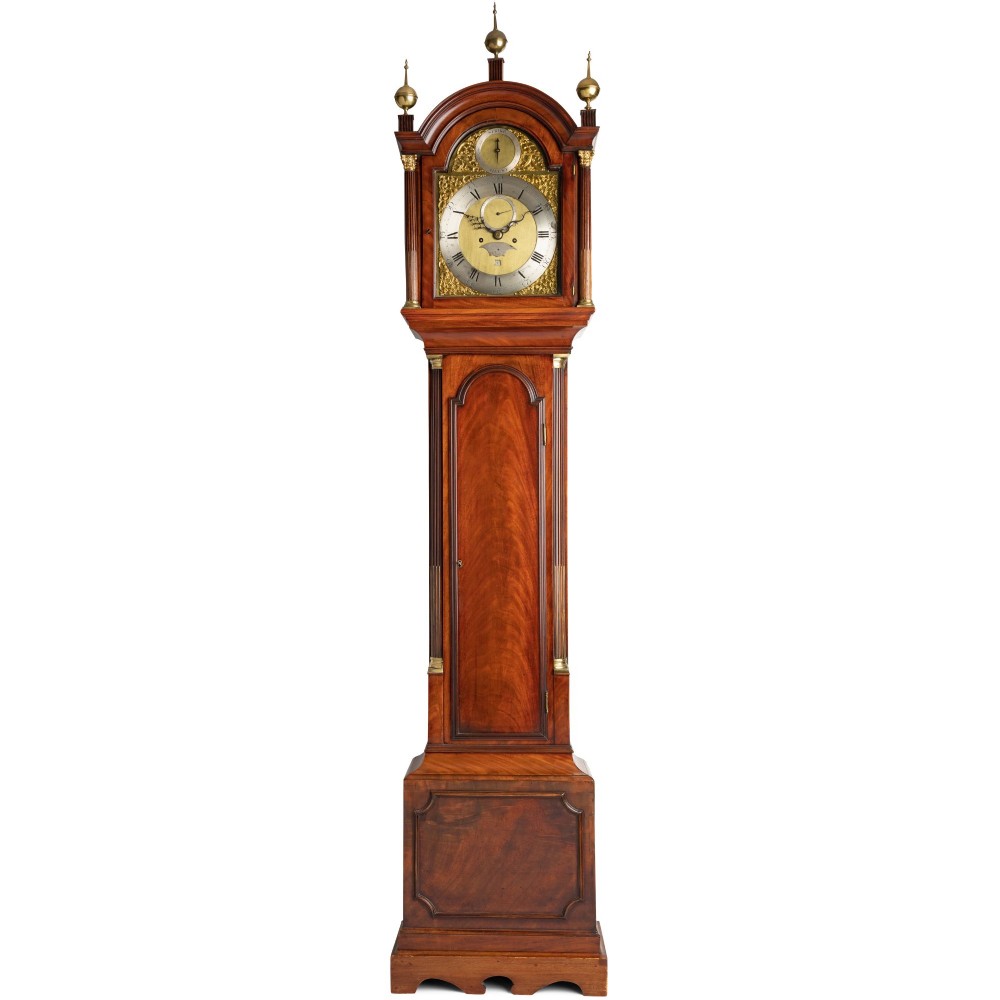 A Georgian flame mahogany longcase clock featuring an arched hood with three brass finials and an engraved brass dial.