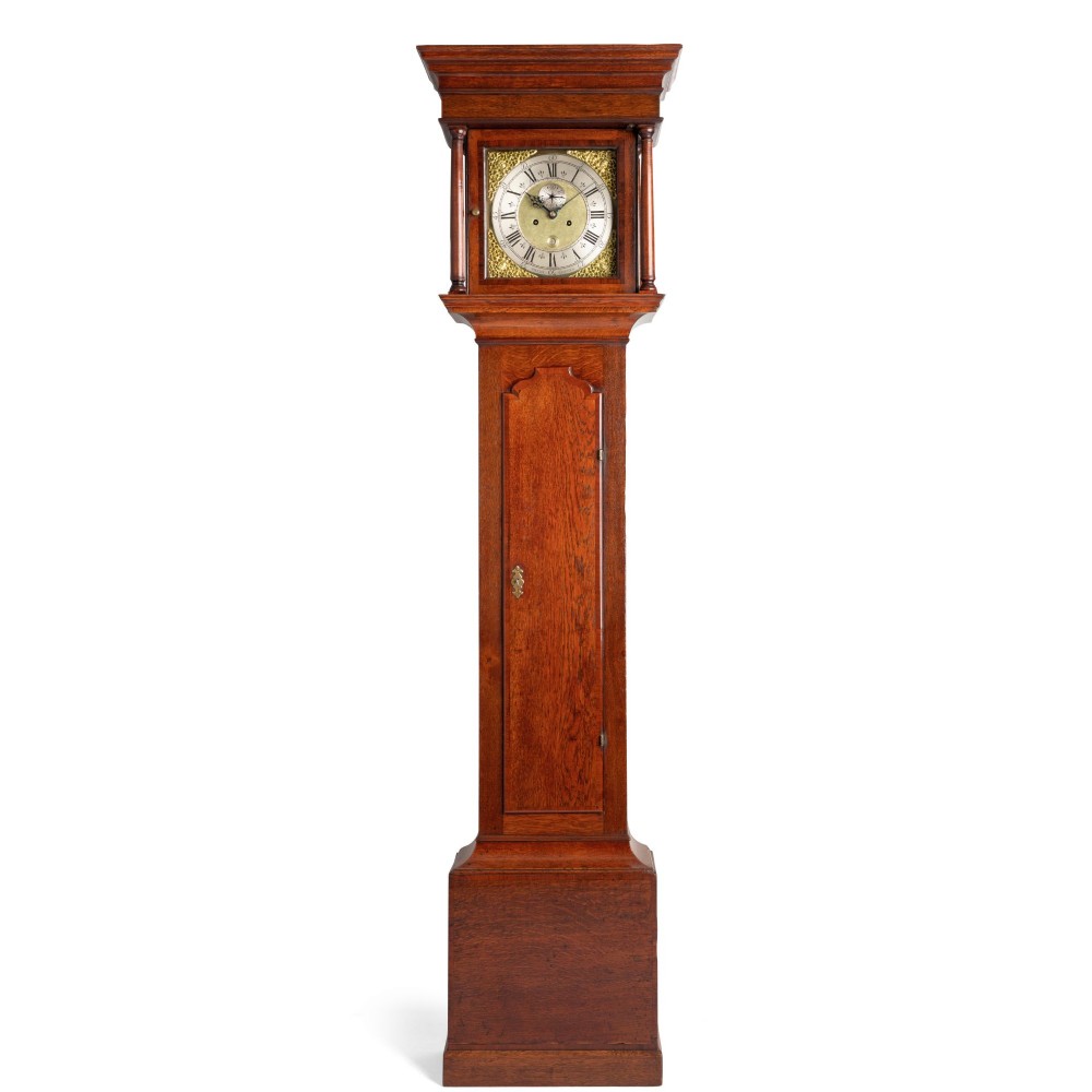 An antique Georgian oak longcase clock featuring a square brass dial with Roman numerals and turned hood columns.