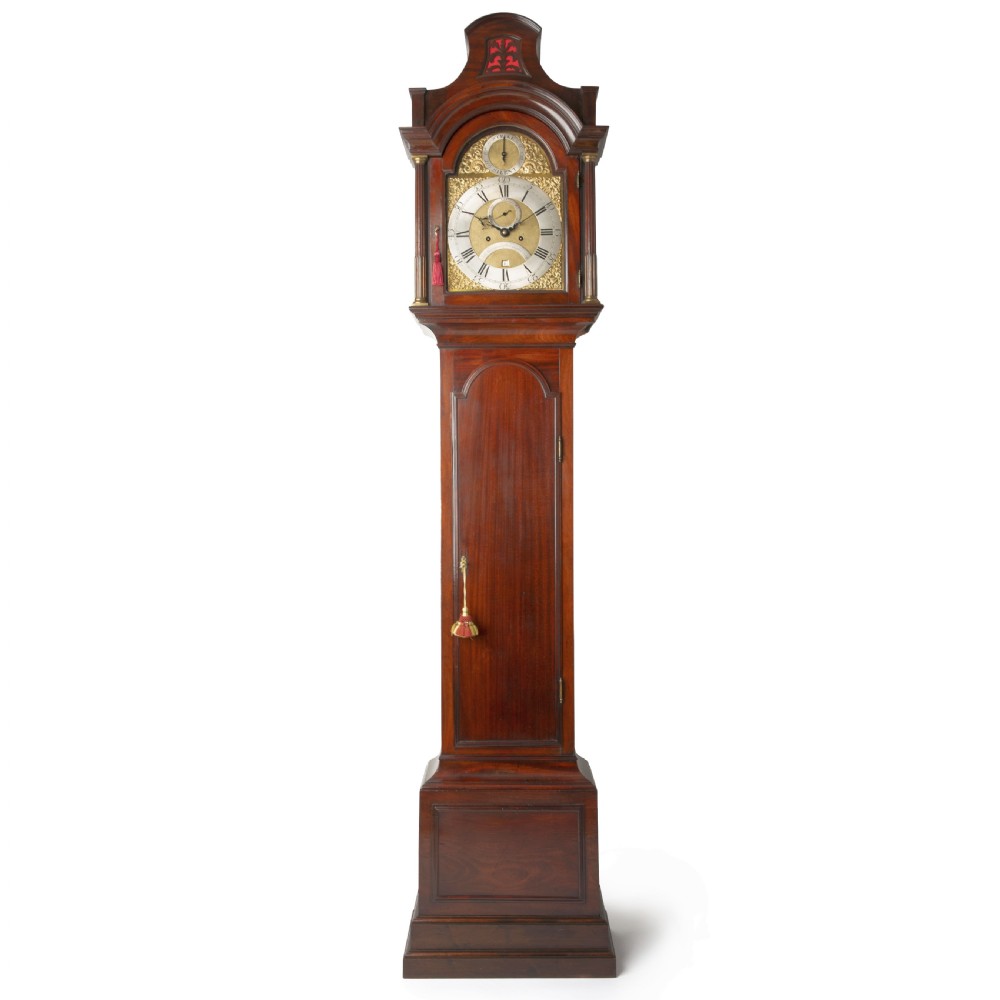 A tall Georgian mahogany longcase clock featuring a pagoda hood, brass decorative spandrels, a silvered dial, and a polished wooden case.