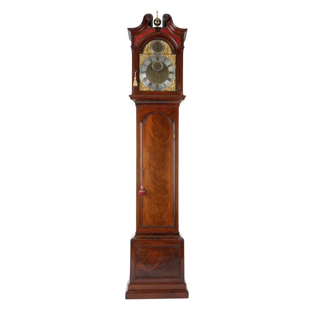 An 18th-century Georgian mahogany longcase clock featuring an arched hood with a brass finial, a gilded brass dial, and a flame mahogany trunk door.