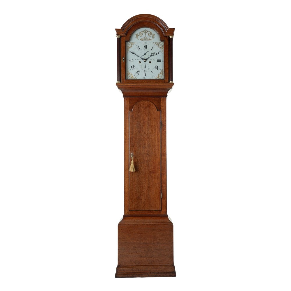 An antique oak longcase clock featuring a rounded arched hood, a white painted dial with Roman numerals, and a tall slender trunk set on a plinth base.