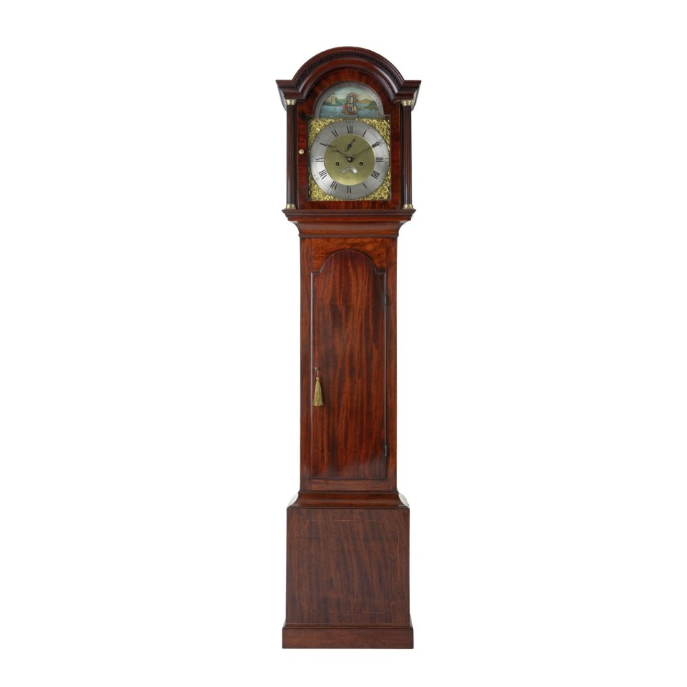 An antique Georgian flame mahogany longcase clock featuring an arched hood with brass-capped pillars and a silvered brass dial topped with a painted rocking ship automaton.