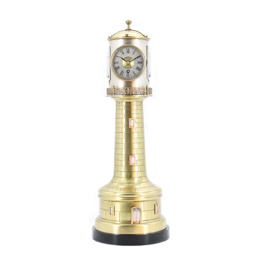 A late nineteenth-century French brass and silvered metal automaton clock styled in the shape of a lighthouse on a black base.