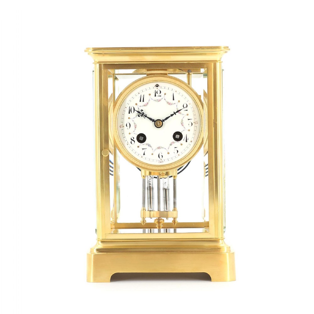 A late nineteenth-century French four-glass mantel clock in a gilt-brass case featuring an enamelled dial with floral decoration and a visible mercury pendulum.