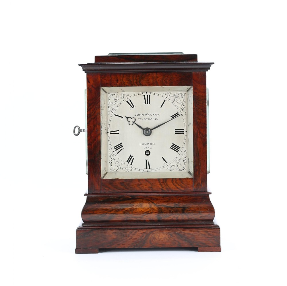 An antique mahogany five-glass library clock featuring a silvered dial with Roman numerals, corner engravings, and a stepped plinth base.