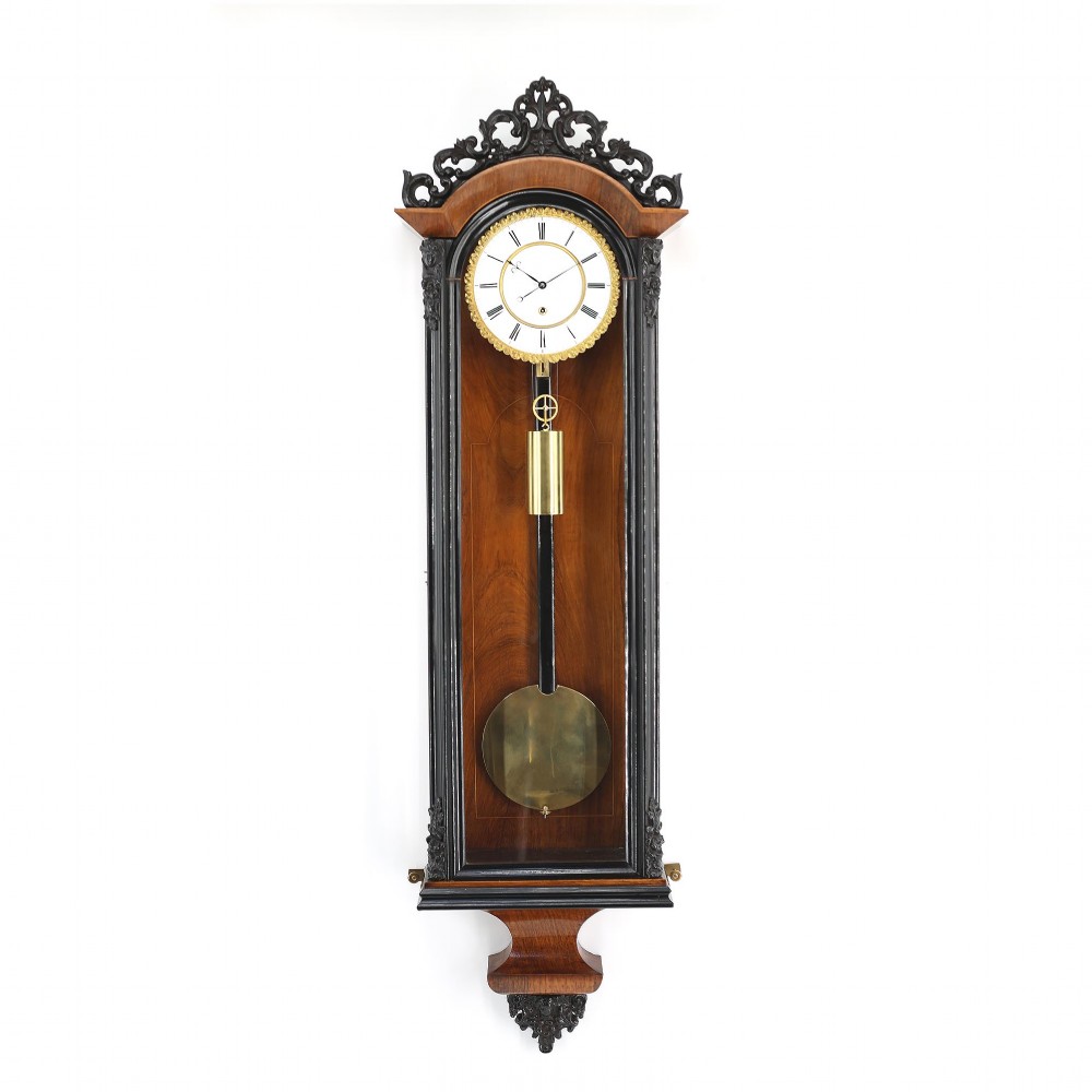An antique Vienna regulator wall clock in a glazed walnut case with ebonised trim, Roman numeral dial, and brass pendulum.