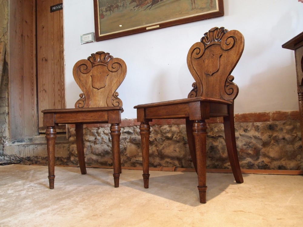 Chairs pair of William IV carved Oak hall chairs c1835