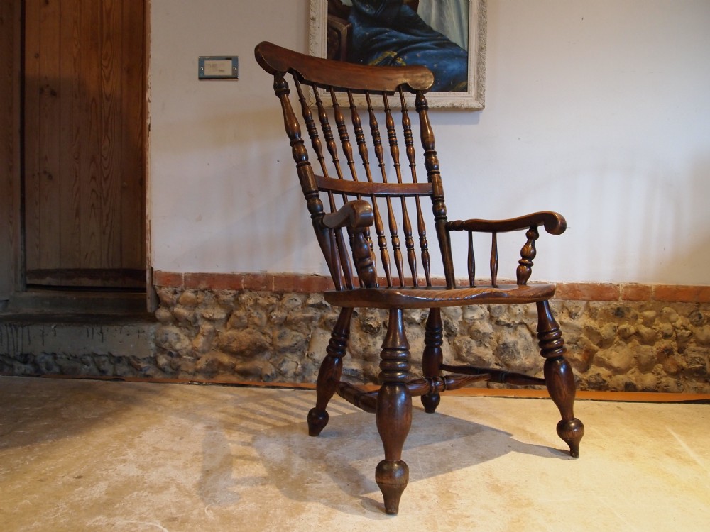 A dark brown Victorian Lincolnshire Windsor armchair featuring a turned spindle back, shaped crest rail, curved armrests, and turned legs with stretchers. View III