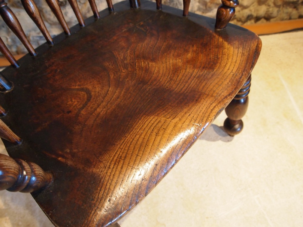 A dark brown Victorian Lincolnshire Windsor armchair featuring a turned spindle back, shaped crest rail, curved armrests, and turned legs with stretchers. View VII