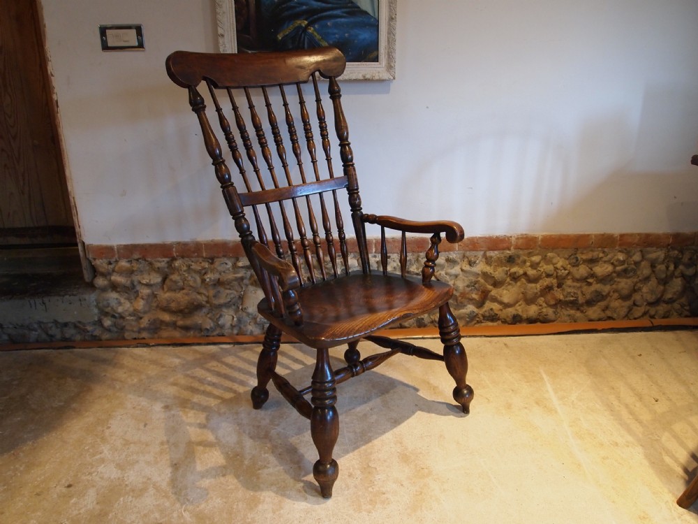 A dark brown Victorian Lincolnshire Windsor armchair featuring a turned spindle back, shaped crest rail, curved armrests, and turned legs with stretchers. View X