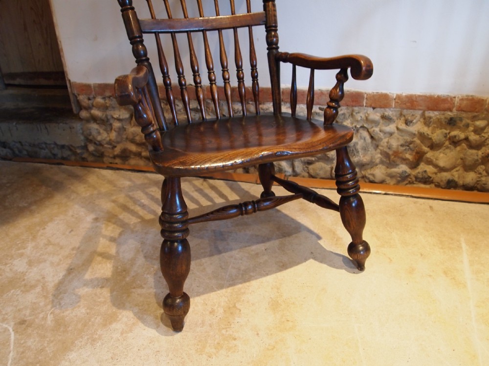 A dark brown Victorian Lincolnshire Windsor armchair featuring a turned spindle back, shaped crest rail, curved armrests, and turned legs with stretchers. View XI