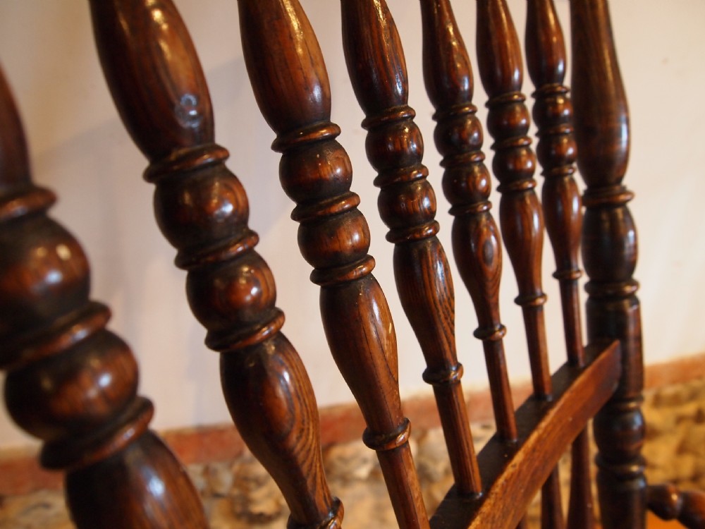 A dark brown Victorian Lincolnshire Windsor armchair featuring a turned spindle back, shaped crest rail, curved armrests, and turned legs with stretchers. View XII