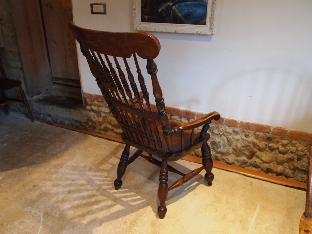 A dark brown Victorian Lincolnshire Windsor armchair featuring a turned spindle back, shaped crest rail, curved armrests, and turned legs with stretchers. View XIII