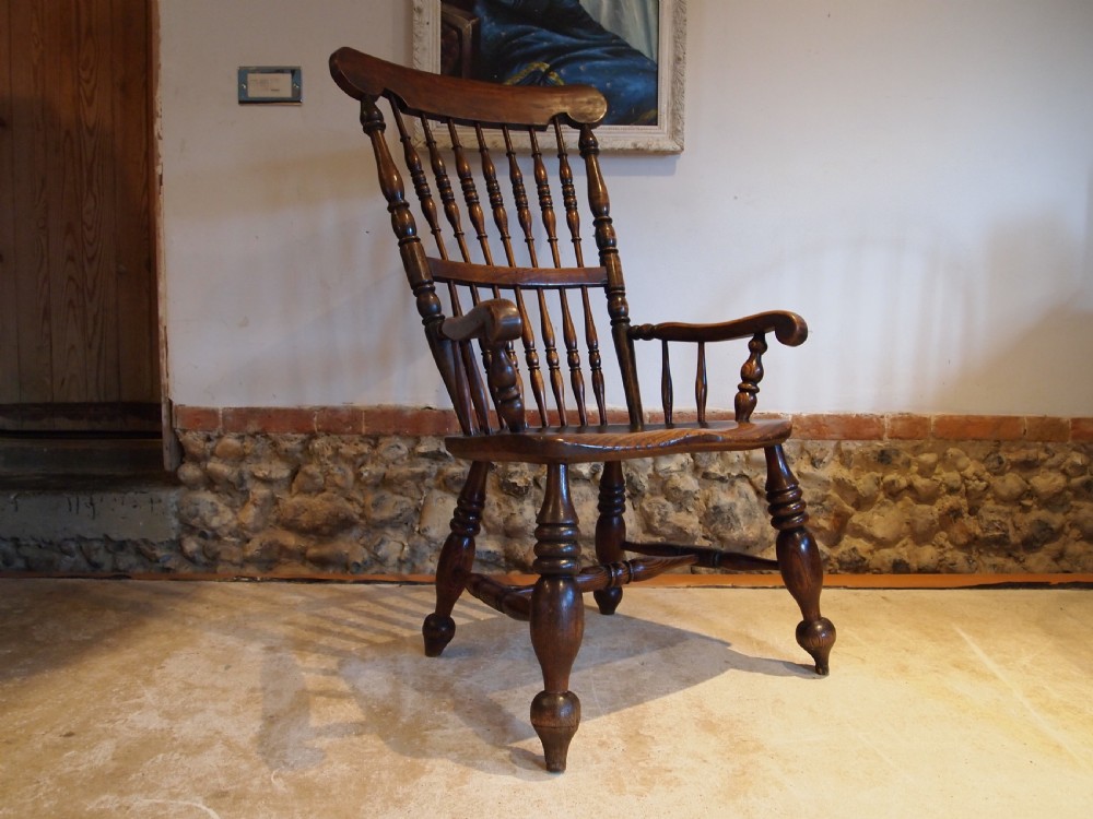 A dark brown Victorian Lincolnshire Windsor armchair featuring a turned spindle back, shaped crest rail, curved armrests, and turned legs with stretchers. View XIV