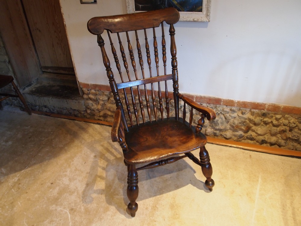 A dark brown Victorian Lincolnshire Windsor armchair featuring a turned spindle back, shaped crest rail, curved armrests, and turned legs with stretchers. View XV
