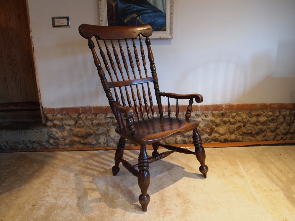 A dark brown Victorian Lincolnshire Windsor armchair featuring a turned spindle back, shaped crest rail, curved armrests, and turned legs with stretchers. View XVI