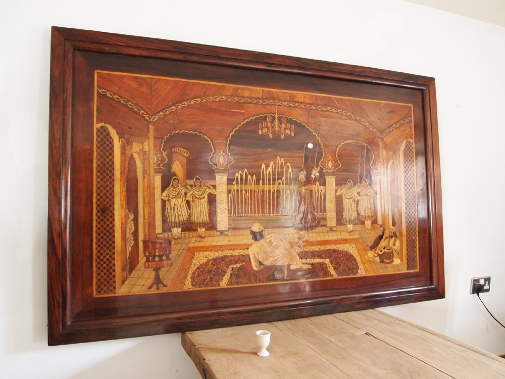 A large rectangular Indian specimen wood marquetry panel depicting a detailed court performance scene framed in dark polished wood. View X