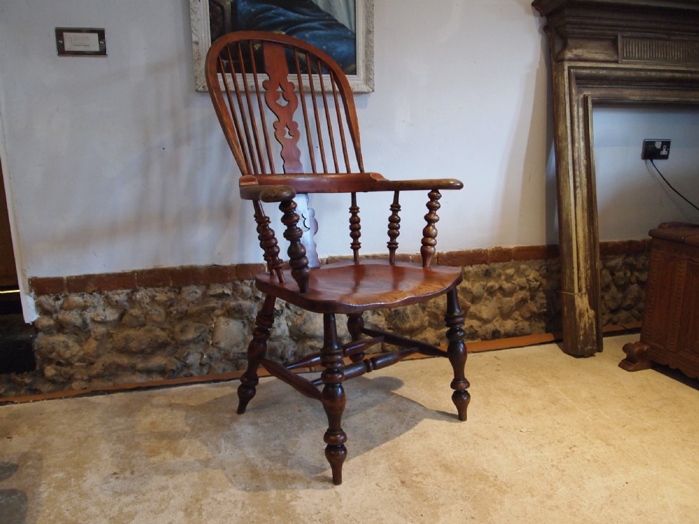A Victorian wooden Windsor armchair with a high hoop back, central pierced splat, turned spindles, and turned legs with stretchers.