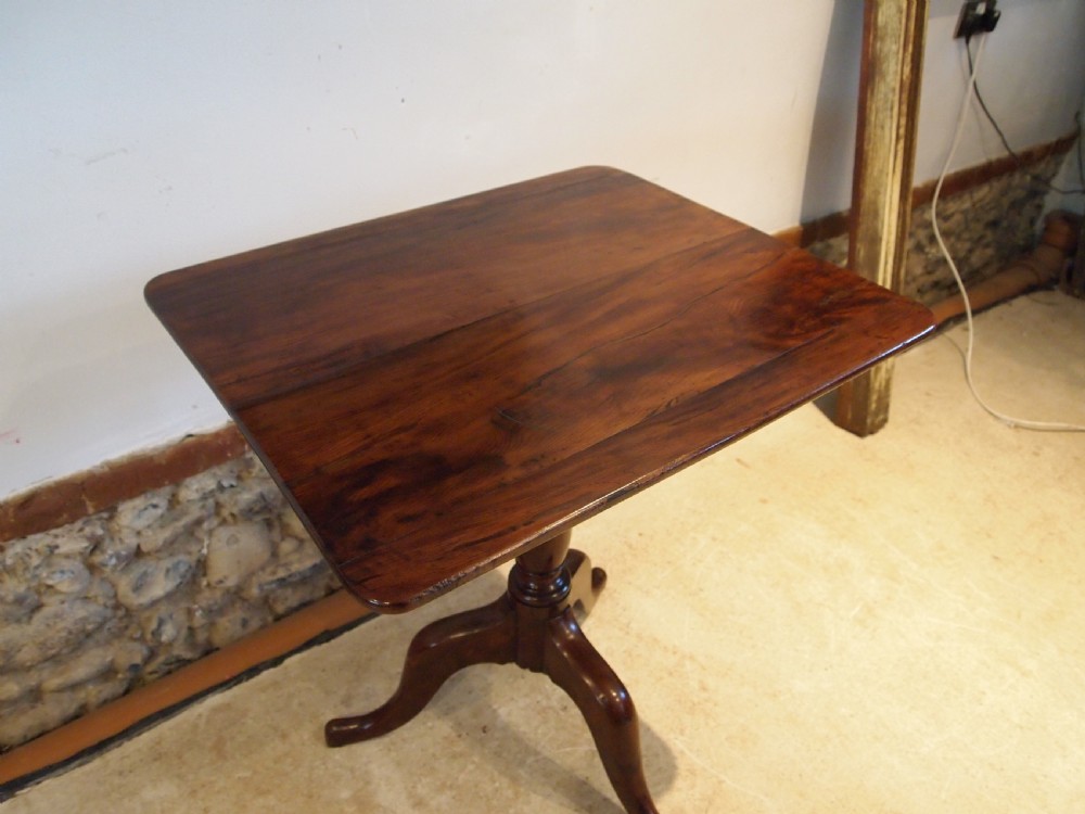 A George III yew wood tripod table featuring a rectangular top supported by a turned central column and three curved cabriole legs.