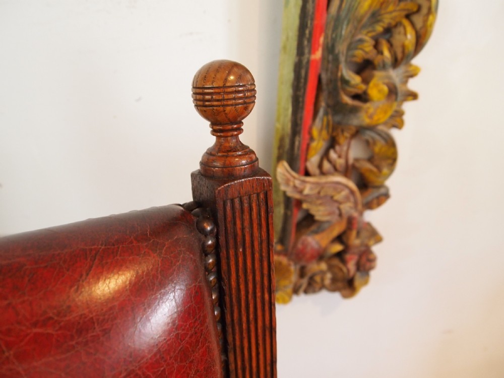 An early Victorian oak armchair with button-tufted chestnut brown leather upholstery, spindled arm supports, turned front legs, and brass casters. View V