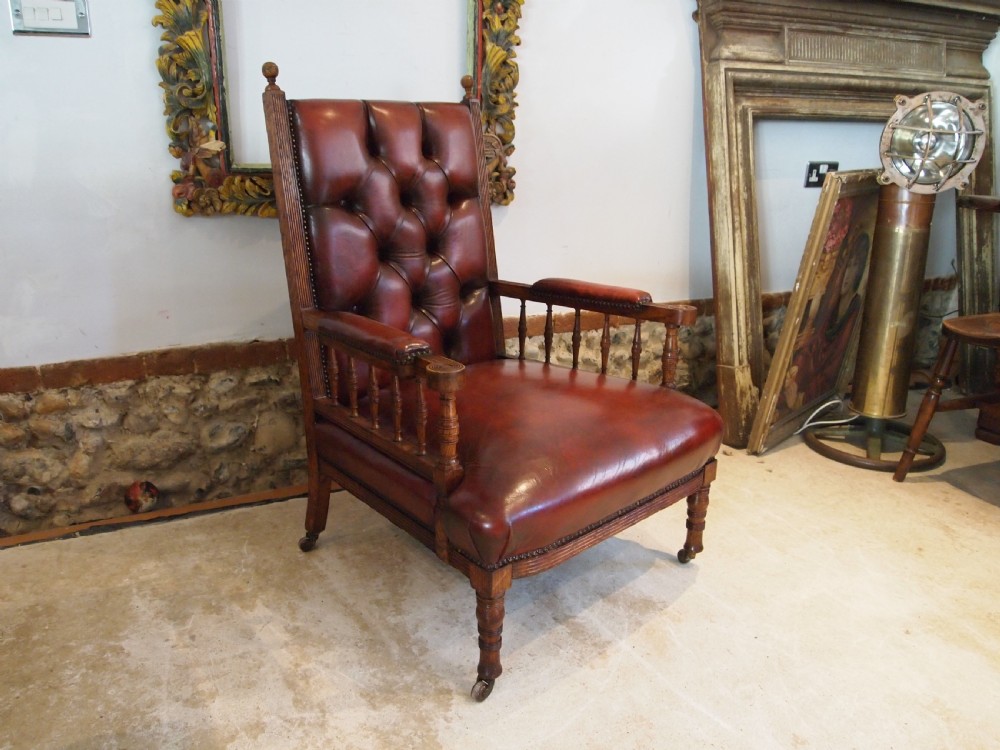 An early Victorian oak armchair with button-tufted chestnut brown leather upholstery, spindled arm supports, turned front legs, and brass casters. View VI