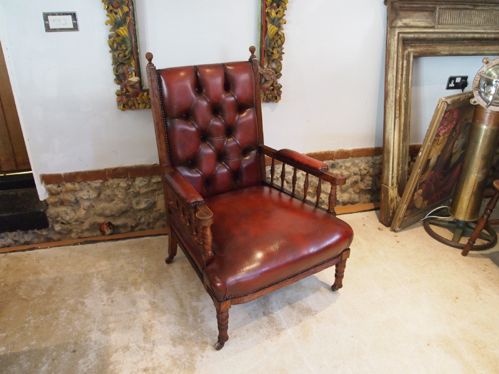An early Victorian oak armchair with button-tufted chestnut brown leather upholstery, spindled arm supports, turned front legs, and brass casters. View IX