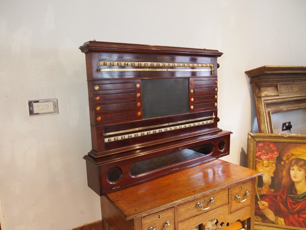 A Victorian mahogany snooker scoreboard featuring brass tracking rails, numbered rollers, a central chalkboard, and a glass-fronted lower cabinet.