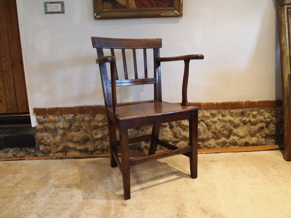 A George IV period dark elm Windsor armchair featuring a rectangular top rail, vertical back splats, shaped armrests, a solid seat, and square legs joined by stretchers. View V