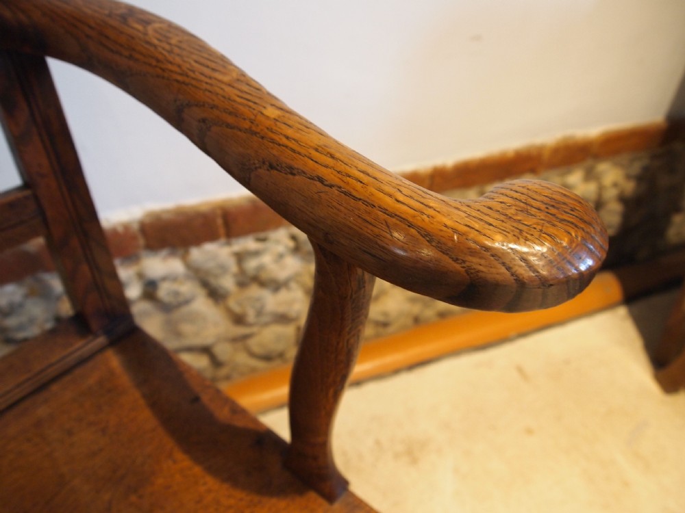 A George IV period dark elm Windsor armchair featuring a rectangular top rail, vertical back splats, shaped armrests, a solid seat, and square legs joined by stretchers. View VII