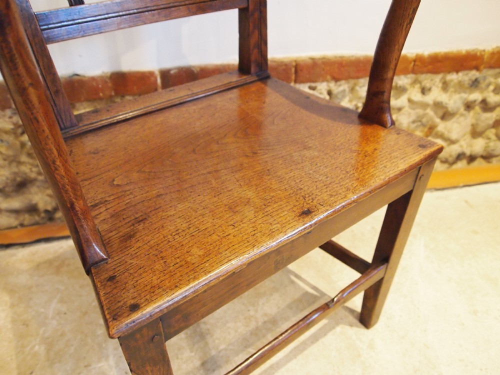 A George IV period dark elm Windsor armchair featuring a rectangular top rail, vertical back splats, shaped armrests, a solid seat, and square legs joined by stretchers. View VIII