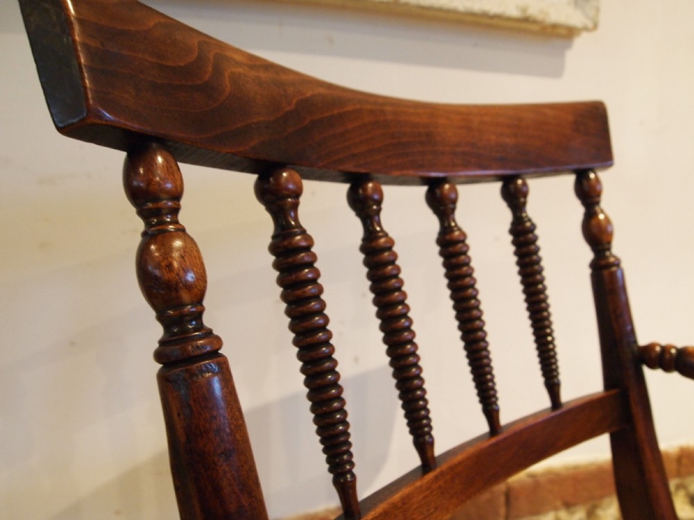 A Victorian wooden Windsor armchair with turned back spindles, shaped armrests, a solid timber seat, and turned legs. View II
