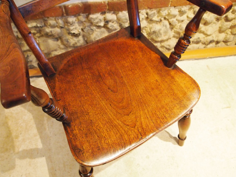 A Victorian wooden Windsor armchair with turned back spindles, shaped armrests, a solid timber seat, and turned legs. View III