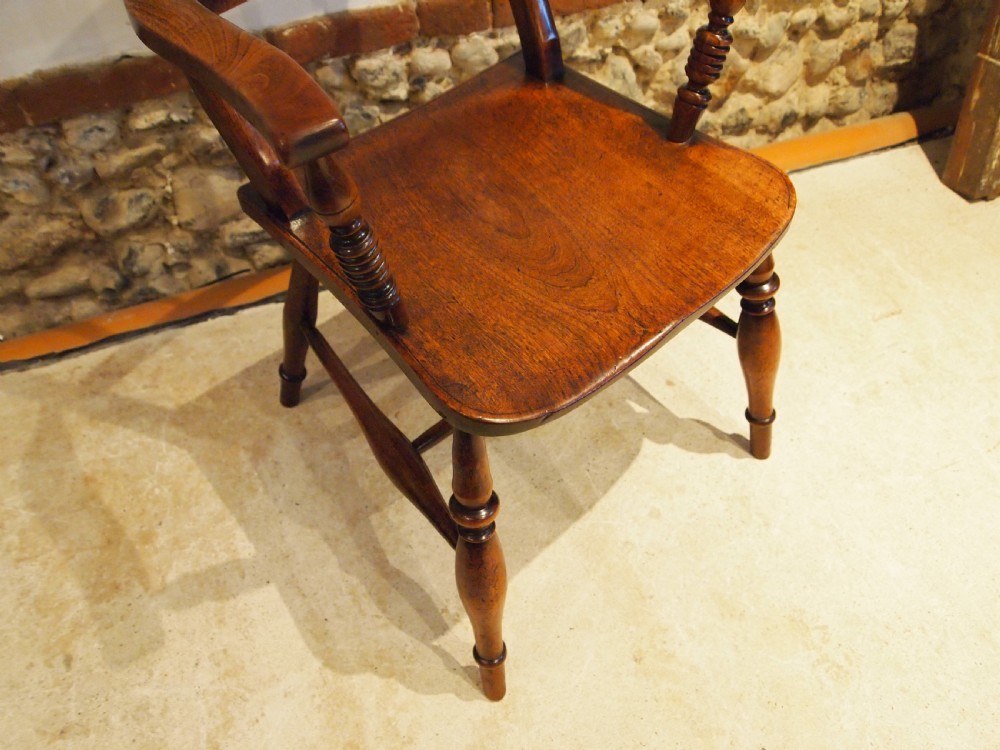 A Victorian wooden Windsor armchair with turned back spindles, shaped armrests, a solid timber seat, and turned legs. View VI
