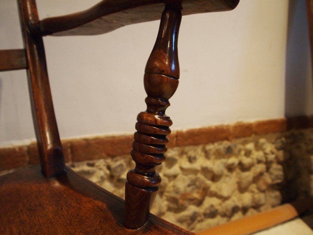 A Victorian wooden Windsor armchair with turned back spindles, shaped armrests, a solid timber seat, and turned legs. View VII