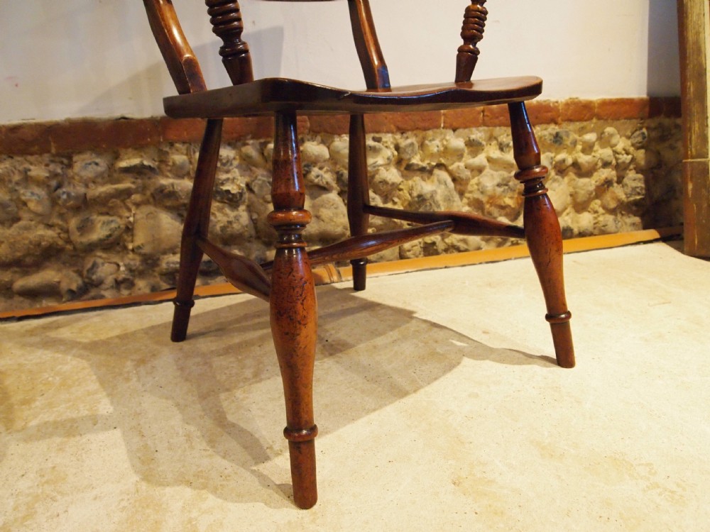 A Victorian wooden Windsor armchair with turned back spindles, shaped armrests, a solid timber seat, and turned legs. View VIII
