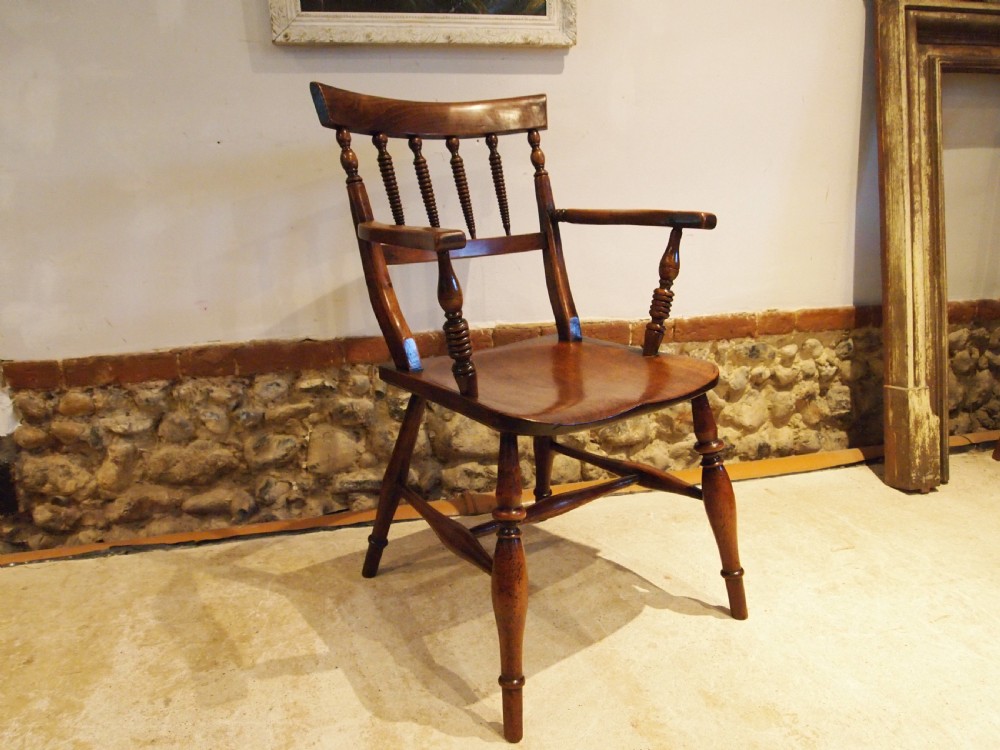 A Victorian wooden Windsor armchair with turned back spindles, shaped armrests, a solid timber seat, and turned legs. View X