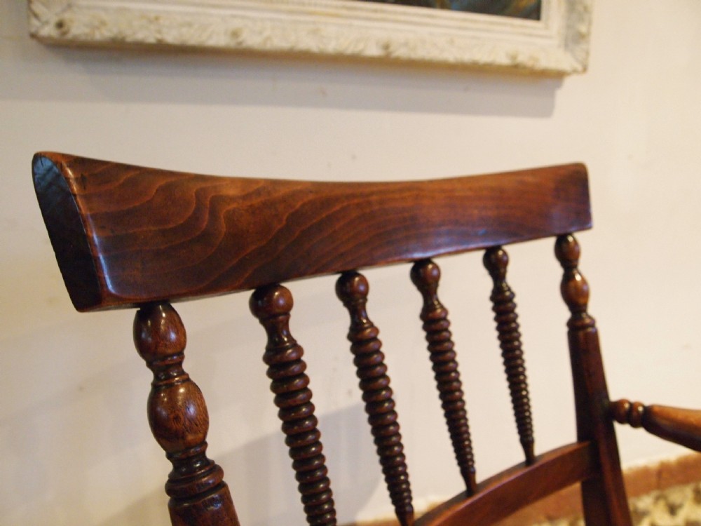 A Victorian wooden Windsor armchair with turned back spindles, shaped armrests, a solid timber seat, and turned legs. View XIII