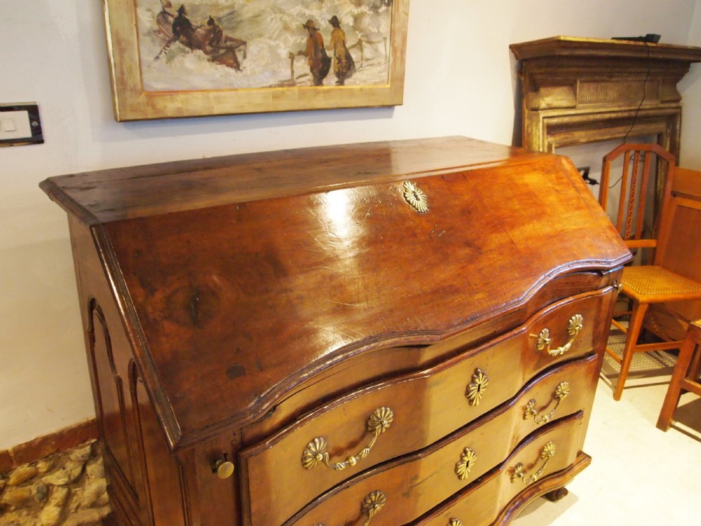 An 18th-century French walnut slant-front bureau desk featuring three wide drawers with ornamental brass handles and keyhole escutcheons. View VII