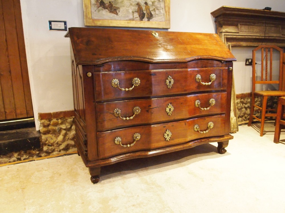 An 18th-century French walnut slant-front bureau desk featuring three wide drawers with ornamental brass handles and keyhole escutcheons. View X