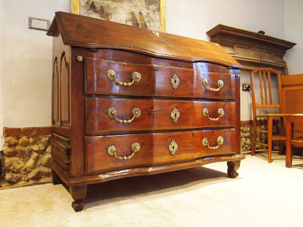 An 18th-century French walnut slant-front bureau desk featuring three wide drawers with ornamental brass handles and keyhole escutcheons. View XIX