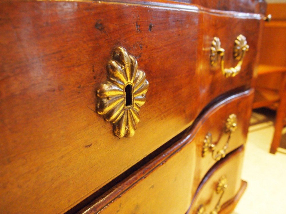 An 18th-century French walnut slant-front bureau desk featuring three wide drawers with ornamental brass handles and keyhole escutcheons. View XXII