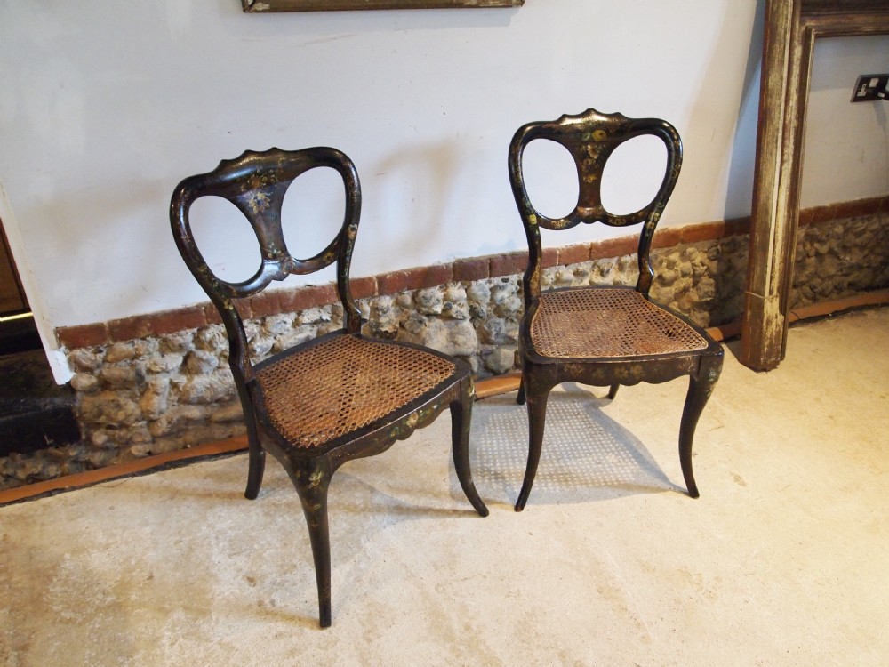 A pair of black Victorian side chairs featuring hand-painted floral details, balloon backrests, and woven cane seats. View III