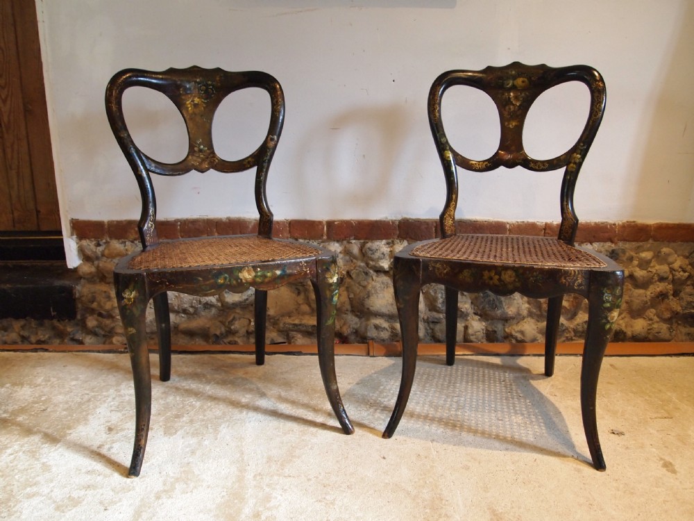 A pair of black Victorian side chairs featuring hand-painted floral details, balloon backrests, and woven cane seats. View VI